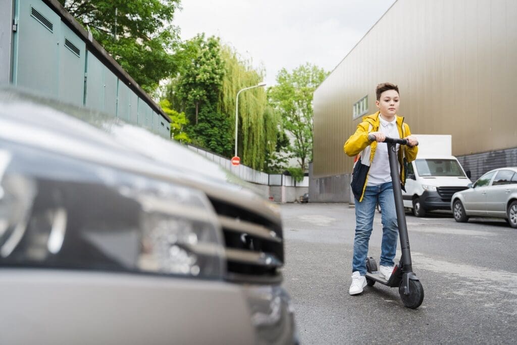 The Most Common Micromobility Lawsuits blog. Image of a teen riding an escooter on a public street.
