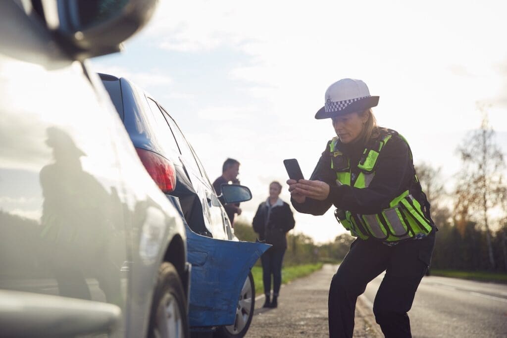 Female Traffic Police Officer Taking Photos On Mobile Phone At Road Traffic Accident