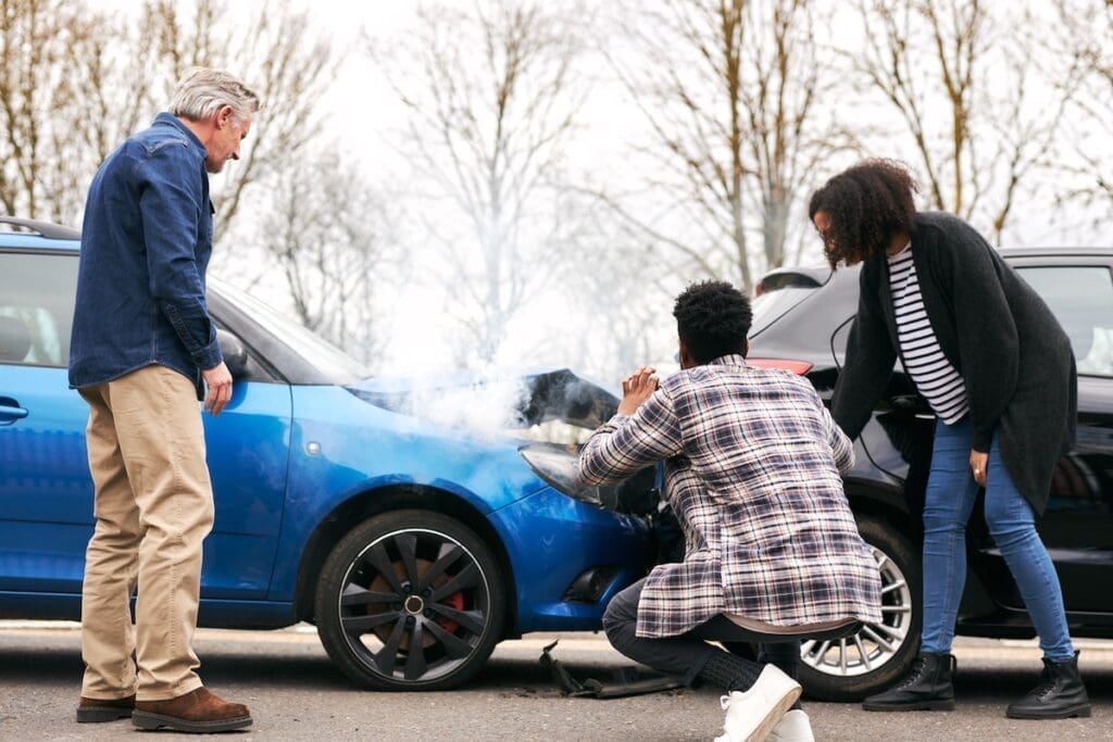 Young couple take photos on mobile phone of damage to car in accident with senior driver