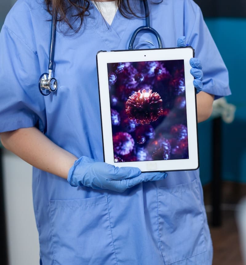 Closeup of practitioner woman nurse holding tablet computer with virus expertise result on screen discussing medical treatment with african american doctor in hospital office. Health care service